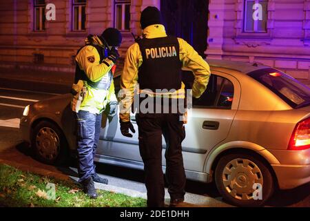 Polizeibeamte halten einen Protestierenden in einem Auto in der Nähe des slowenischen parlamentsgebäudes während eines regierungsfeindlichen Protestes an.die regierungsfeindlichen Proteste in der slowenischen Hauptstadt gingen weiter, und Demonstranten, die zuvor Regierungsgebäude umherfuhren, fuhren jetzt mit ihren Autos, um die covid-19-Epidemie-Beschränkungen zu respektieren. Vor allem das Verbot von Versammlungen, die mit sehr hohen Geldstrafen belegt sind. Viele wurden dennoch von der Polizei gebucht und mit Geldstrafen belegt, was viele als einen Schritt einer anderen Regierung nehmen, um die Proteste zu kriminalisieren. Stockfoto