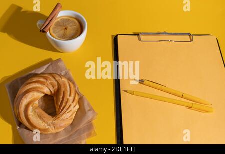 Kuchen, Tasse Tee oder Glühwein und Lebenslauf Blatt auf der Fortuna Gold Gelb Farbe Hintergrund, Draufsicht. Stockfoto