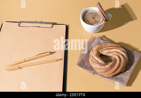 Kuchen, Tasse Tee oder Glühwein und Lebenslauf Blatt auf dem Set Segel Champagner Farbe Hintergrund, Draufsicht. Stockfoto