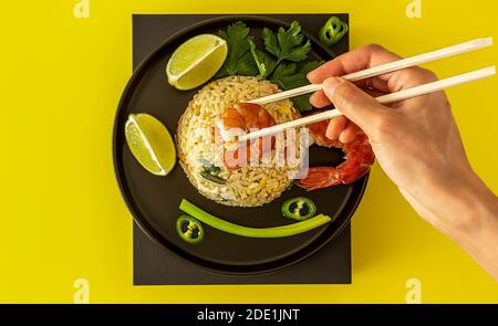 Hand mit Essstäbchen essen Thailand Khao Pad Khun oder gebratenen Reis mit Garnelen. Stockfoto