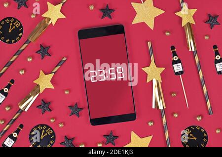Silvester Festkonzept mit Smartphone mit Timer Countdown bis Mitternacht zwischen Party-Elemente wie Papier Trinkhalme und Papierchampaign bot Stockfoto