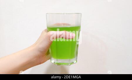 Hand hält ein Glas vibrierenden grünen Limonade Getränk. Stockfoto