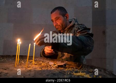 STEPANAKERT, BERG-KARABACH - 05. NOVEMBER: Ein Soldat der Arzakh Defense Army zündet Kerzen in der Kathedrale der Heiligen Mutter Gottes an, Auch bekannt als Surb Astvatsamor Hovanu Kathedrale während eines militärischen Konflikts zwischen armenischen und aserbaidschanischen Truppen in Stepanakert de facto Hauptstadt der selbsternannten Republik Arzakh oder Berg-Karabach de jure Teil der Republik Aserbaidschan am 04. November 2020. Die Kämpfe zwischen Armenien und Aserbaidschan um Berg-Karabach, auch bekannt als die Republik Arzakh, brachen Ende September in einen sechswöchigen Krieg aus, der Tausende Tote hinterließ. Stockfoto