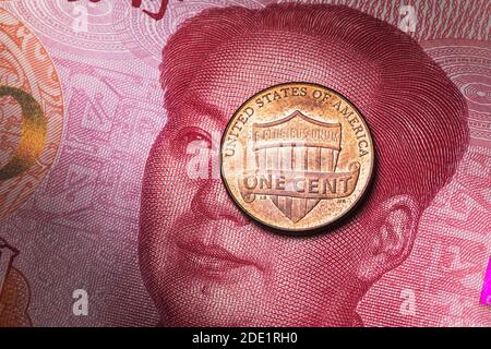 Ein amerikanischer Cent liegt auf dem Hintergrund einer 100 Yuan Banknote, Nahaufnahme. Stockfoto