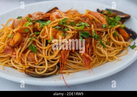 Bunte Spaghetti mit Meeresfrüchten. Traditionelles mediterranes Gericht, Taverne am Manganari Beach, Insel iOS, Griechenland. Stockfoto