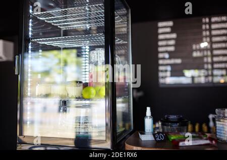 Verschwommenes Bild von Showcase im Café-Shop. Kuchen und Krug mit Getränk auf den Regalen eines Fensters eines Straßenrestaurants Stockfoto