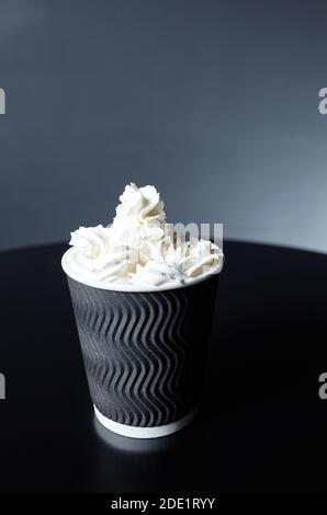 Einweg-Pappbecher mit leckeren Kaffee trinken mit Milch und Schlagsahne auf Holztisch im Café Stockfoto