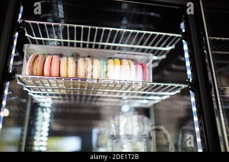 Verschwommenes Bild von Showcase im Café-Shop. Bunte Makronen in Box auf den Regalen eines Fensters eines Straßenrestaurants Stockfoto