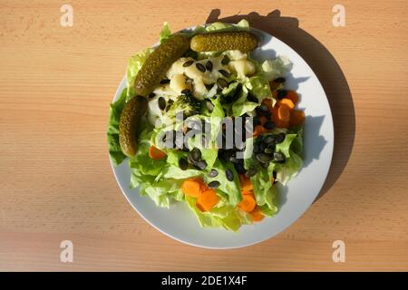 Vitaminbombe auf dem Teller in Form eines gemischten knackigen Salats mit Kürbiskernen von oben Stockfoto