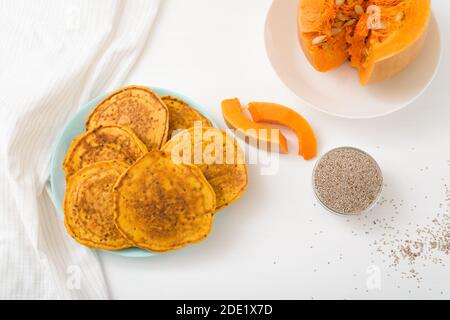Ein Stapel von Herbst Kürbis Pfannkuchen mit Chia Samen und Honig auf einem hellen Hintergrund. Köstliche gesunde vegetarische Ernährung Frühstück. Das Konzept der Einnahme Stockfoto