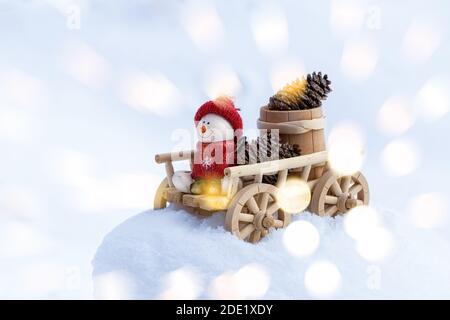 Festliche Weihnachten Hintergrund mit Schneemann auf einem Holzkarren. Glücklicher Schneemann im Winter weihnachtslandschaft. Frohe Weihnachten und frohe Feiertage Gruß c Stockfoto