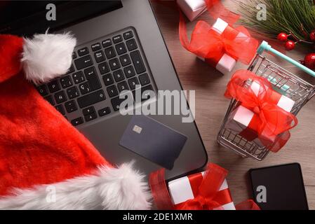 Konzeptionelle Internet weihnachten Shopping Hintergrund mit Laptop, Karte, Warenkorb und Geschenke. Draufsicht. Horizontale Zusammensetzung. Stockfoto