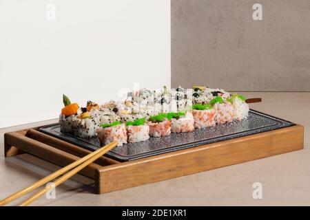 Nahaufnahme eines Sortiments von appetitlichen Uramaki-Stücken auf einem Tablett mit Holzstäbchen. Sushi und gesundes Essen Konzept. Stockfoto