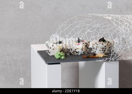 Künstlerische Nahaufnahme von köstlich aussehenden Uramaki mit Wasabi auf einem Schiefertablett mit Dekorationen. Sushi und abstraktes Konzept. Stockfoto