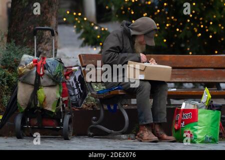 Ein Obdachloser sitzt auf einer Bank und schaut durch Seine persönlichen Besitztümer Stockfoto