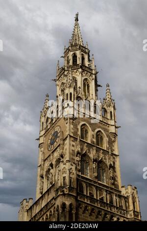 Low-Angle-Ansicht des Details des Glockenturms des neugotischen Neuen Rathauses auf dem Marienplatz, München, Bayern, Deutschland gegen einen bewölkten Himmel gesetzt Stockfoto