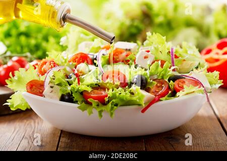 Kochen Salat. Olivenöl Gießen in Schüssel mit frischem Gemüsesalat Stockfoto