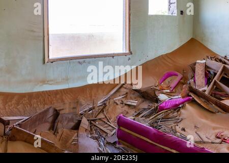 Abgerissene Inneneinrichtung im Sand, mit zerbrochenen Möbeln, im Geisterdorf Al Madam in Sharjah, Vereinigte Arabische Emirate. Stockfoto