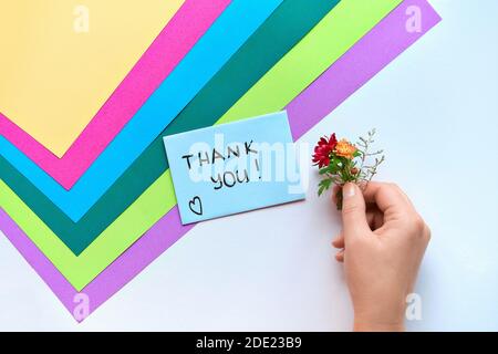 Internationaler Danktag. Grußkarte mit weiblicher Hand hält Umschlag mit Herzform und Blumen. Vielen Dank Textkarte und Hand mit Blumen. Stockfoto