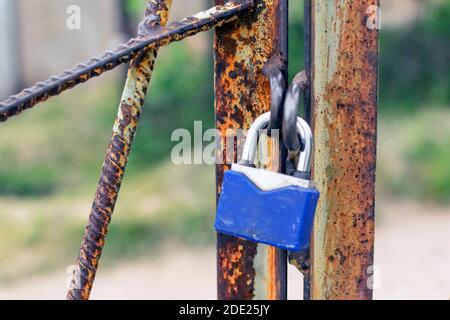 Ein Vorhängeschloss hängt an einem rostigen Tor. Sicherheitskonzept, Datenschutz, Passwort und Account Hacking. Heben Sie die Schlüssel für das Schloss. Stockfoto