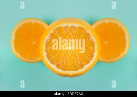 Hellorangefarbener Zellstoff mit zwei Scheiben an den Seiten, die eine elegante geometrische Komposition auf einem blauen Papiertextur-Hintergrund bilden. Kreatives Kochen. Stockfoto