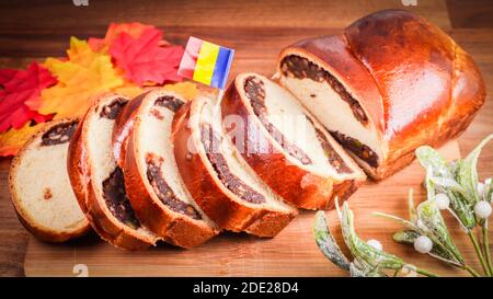 Eine Nahaufnahme von Schokoladenbrot mit rumänischer Flagge, Herbstblättern und dekorativen Grüns Stockfoto