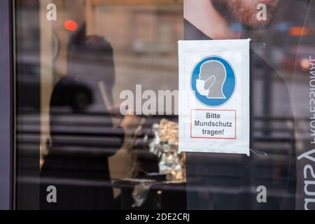 Passau, Deutschland. November 2020. "Bitte tragen Sie einen Mundschutz" steht vor einem Friseur, der die Haare eines Kunden färbt. Angesichts des starken Anstiegs der Coronainfektionen sind in Passau seit Samstag strenge Ausreisebeschränkungen in Kraft.Quelle: Lino Mirgeler/dpa/Alamy Live News Stockfoto