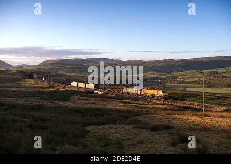 Freightliner Baureihe 90 Elektrolokomotiven führen einen intermodalen Container doppelt Zug durch die Landschaft auf der West Cost Hauptlinie in Cumbria Stockfoto