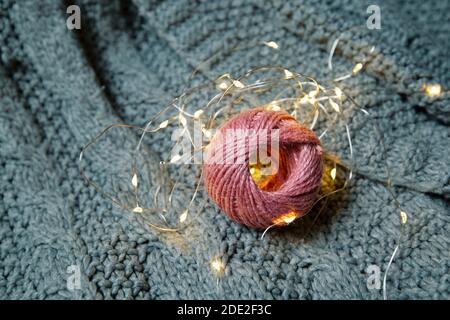 Ball aus rosa Wolle auf einem grauen Strickpullover Stockfoto