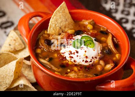 Nahaufnahme einer Schüssel mit Chicken Taco Suppe mit gekrönt Saure Sahne und Chilischoten mit Tortilla-Chips Stockfoto