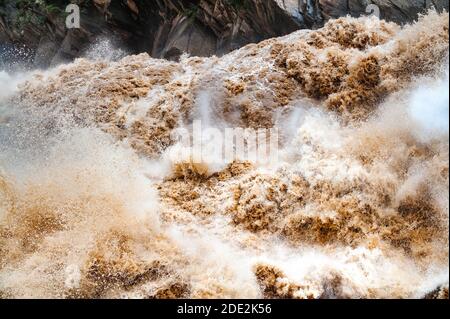 Riesige Wellen von schlammigem Wasser stürzen in den Stromschnellen der Tigerspringenden Schlucht in Yunnan, China, ineinander. Stockfoto