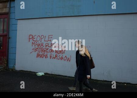 Glasgow, Schottland, Großbritannien, 28. November 2020. Fußgänger passieren neu bemalte Graffiti mit der Aufschrift "People Make Glasgow, Sturgeon won won't break Glasgow", ein Verweis auf die Politik des schottischen Ersten Ministers Nicola Sturgeon, geschrieben auf einer Wand im Wahlkreis von Nicola Sturgeon in Govanhill, im Süden der Stadt. Foto: Jeremy Sutton-Hibbert/ Alamy News. Stockfoto