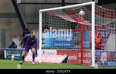 Ryan Boot von Solihull Moors sieht zu, wie Morecambe das dritte Tor, das John O'Sullivan erzielte, während der zweiten Runde des FA Cup im Mazuma Stadium, Morecambe, an ihm vorbeigeht. Stockfoto