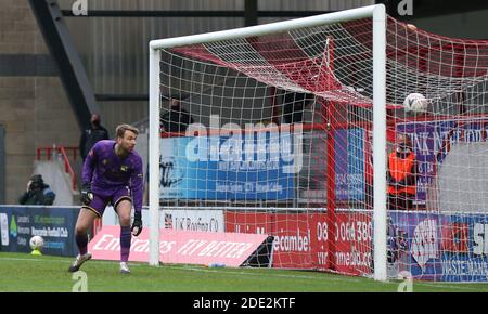 Ryan Boot von Solihull Moors sieht zu, wie Morecambe das dritte Tor, das John O'Sullivan erzielte, während der zweiten Runde des FA Cup im Mazuma Stadium, Morecambe, an ihm vorbeigeht. Stockfoto