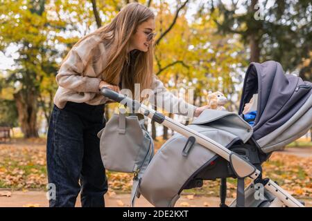 Mama zeigt weiches Spielzeug zu Baby in einem Kinderwagen Stockfoto