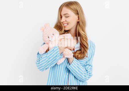 Schöne teen Mädchen im Pyjama Umarmungen ein Plüsch Spielzeug Bunny Stehen auf weißem Hintergrund Stockfoto