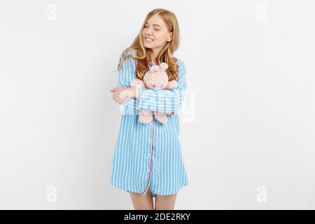 Schöne teen Mädchen im Pyjama Umarmungen ein Plüsch Spielzeug Bunny Stehen auf weißem Hintergrund Stockfoto