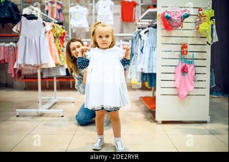 Mutter und kleines Baby versuchen auf Kleid im Geschäft Stockfoto