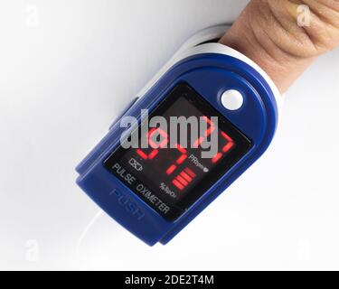 Nahaufnahme eines menschlichen Fingers in einem Pulsoximeter zur Messung des Puls- und Sauerstoffgehalts des Blutes der Person. Stockfoto