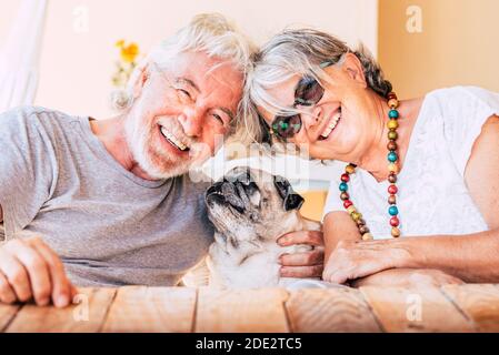 Fröhliches altes Seniorenpaar lächelt und genießt ihre beste Freundin Hund Mops mit Liebe - Konzept der glücklichen reifen Menschen Und Tier - Freude Rentner ältere Lebensfreude Stockfoto