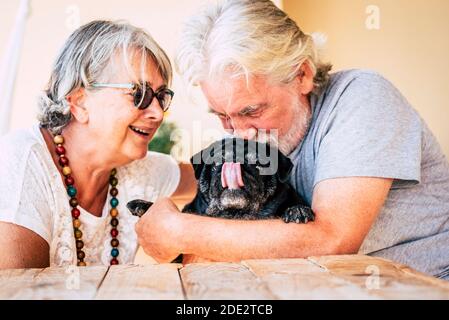 Fröhliches altes Seniorenpaar lächelt und genießt ihre beste Freundin Hund Mops mit Liebe - Konzept der glücklichen reifen Menschen Und Tier - Freude Rentner ältere Lebensfreude Stockfoto