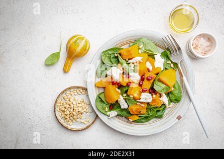 Salat mit geröstetem Kürbis, Käse, Spinat, Pinienkernen und Gewürzen auf weißem Hintergrund, Draufsicht Stockfoto