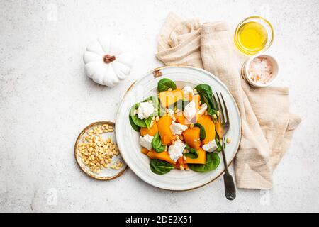 Salat mit geröstetem Kürbis, Käse, Spinat, Pinienkernen und Gewürzen auf weißem Hintergrund, Draufsicht Stockfoto