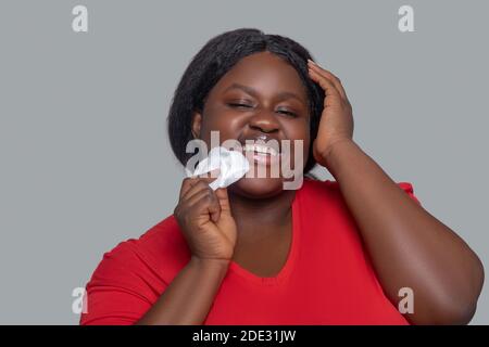 Junge dunkelhäutige Frau hält Schwamm für die Gesichtsreinigung Stockfoto