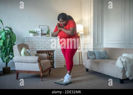 Plus Größe afroamerikanische Frau Überprüfung ihr Gewicht und suchen Schockiert Stockfoto