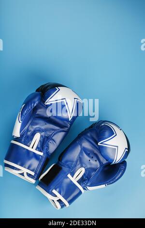 Ein Paar Boxhandschuhe aus Leder auf blauem Hintergrund, freier Platz. Das Konzept des Kampfes und des Kampfes mit Schwierigkeiten. Stockfoto