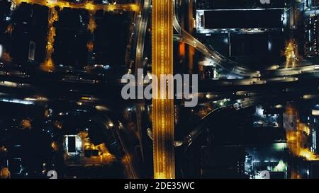 Top down Nacht Stadtverkehr Autobahn an Laternen mit Beleuchtung Stadtbild Luftbild. Downtown Outdoor-Landschaft mit moderner Architektur von Wolkenkratzern Gebäude. Filmische Stadt Philippinen Stockfoto