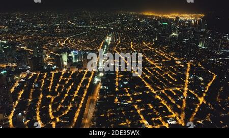 Luftbild der Stadt bei Nacht. Beleuchtete Straßen von Manila Innenstadt an Verkehr Stadt Route. Städtischer Verkehr auf der Autobahn. Moderne Gebäude, Wolkenkratzer mit Neonlicht. Drohne-Filmaufnahme Stockfoto