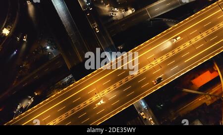 Nahaufnahme von oben nach unten fahren Autos auf der nächtlichen Verkehrsstraße. Philippinische Stadtlandschaft mit Fahrzeugen am Highway. Stadtverkehr auf beleuchteter Autobahn. Blick auf die Straße in der Dämmerung auf die Neonlichter von Manila City Stockfoto