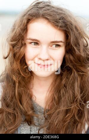 Ein Teenager-Mädchen mit lockigen, langen, braunen Haaren Stockfoto